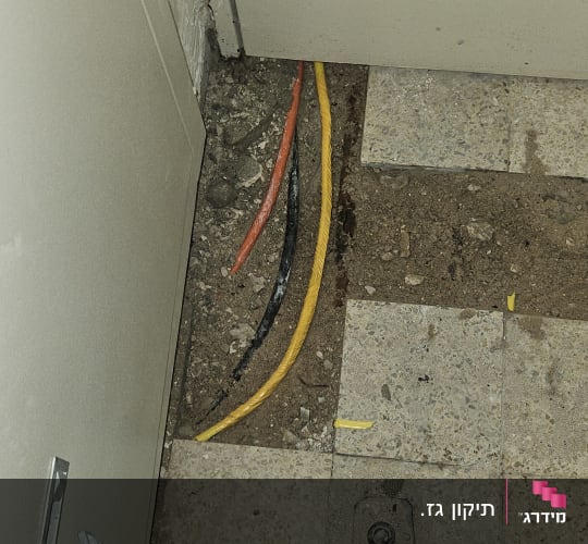 כבלים חשמליים חשופים ברצפה ליד דלת